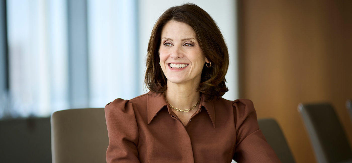 Anna Rotman smiling off in the distance in a conference room